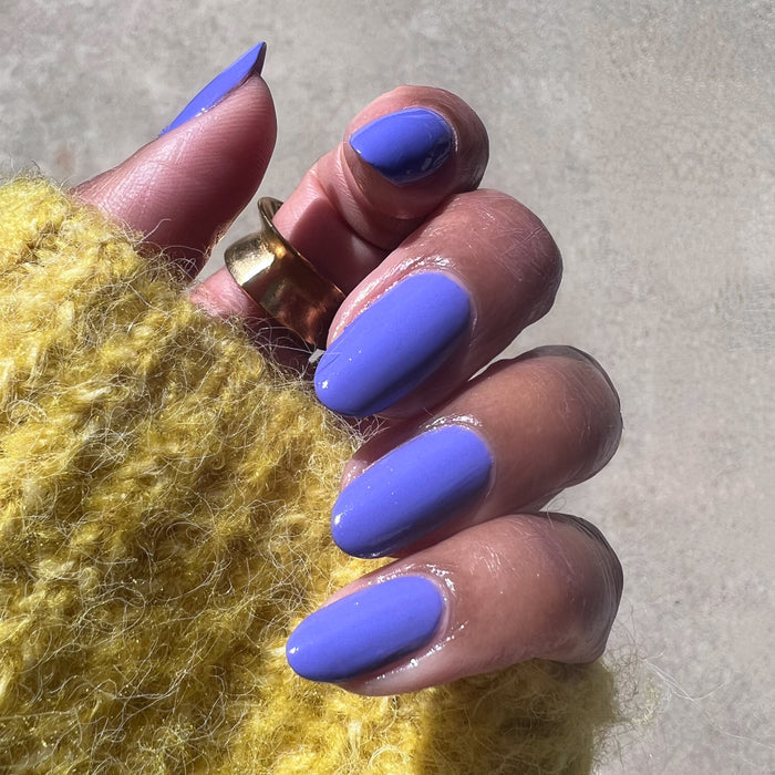 Hand with Royal quick dry polish in smooth glossy lavender purple on natural nails against neutral background