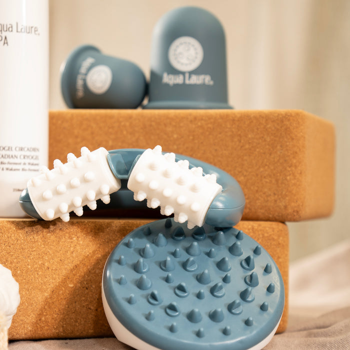 Blue and white facial massage tools with textured rollers and scalp massager for skincare routines, displayed on cork blocks.