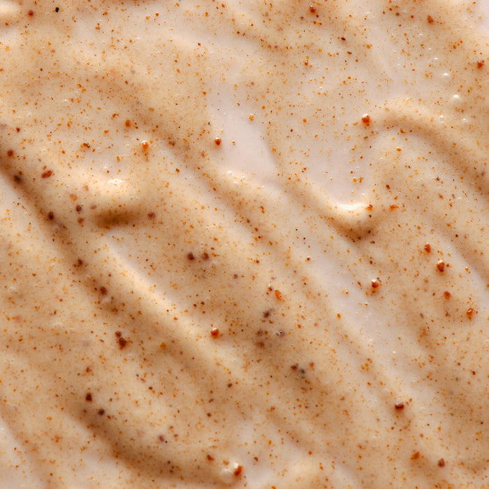 Close-up of creamy skincare product with fine brown exfoliating particles, ideal for gentle skin renewal and texture improvement.