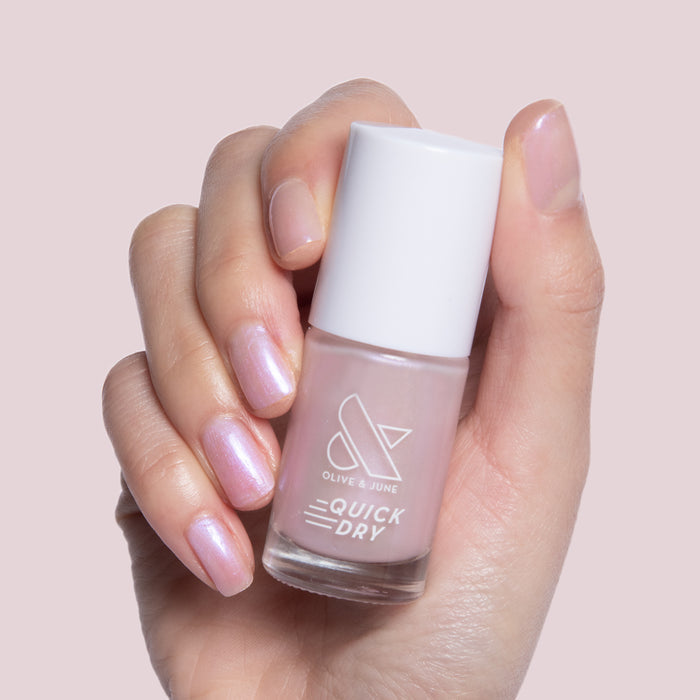 Hand holding Baroque quick dry gel polish bottle with pearly iridescent finish on natural short nails