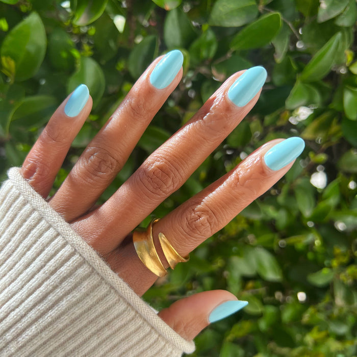 Hand with oval nails painted bright pastel turquoise in Berry Basket gel polish by Olive and June