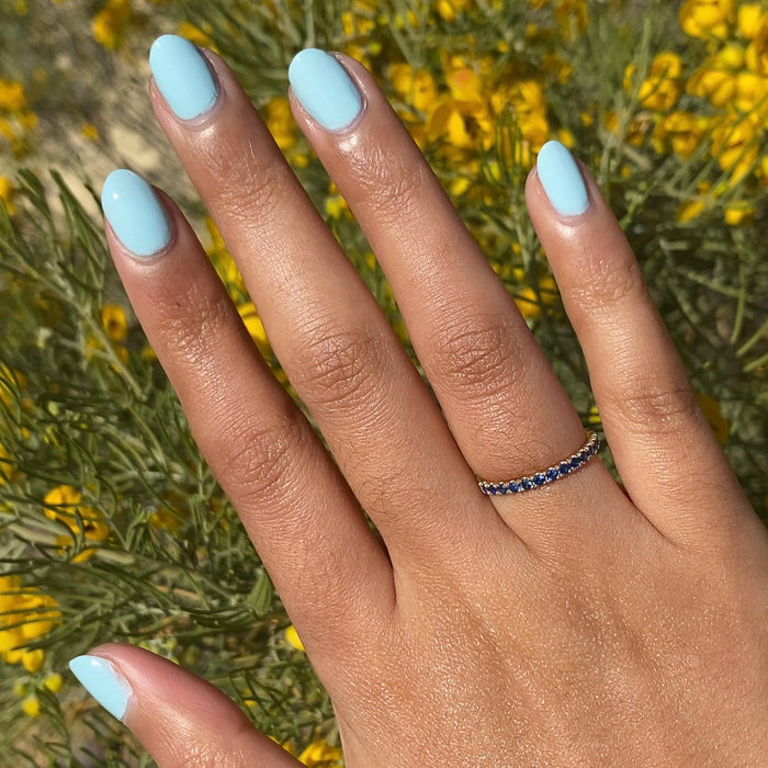 Hand with medium-length almond nails painted pastel turquoise in Berry Basket gel polish by Olive and June outdoors