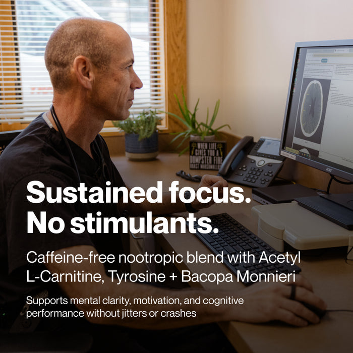 A man sits at a desk working at a computer in an office or clinical setting. Text on the image reads: “Sustained focus. No stimulants.” “Caffeine-free nootropic blend with Acetyl L-Carnitine, Tyrosine + Bacopa Monnieri” “Supports mental clarity, motivation, and cognitive performance without jitters or crashes”