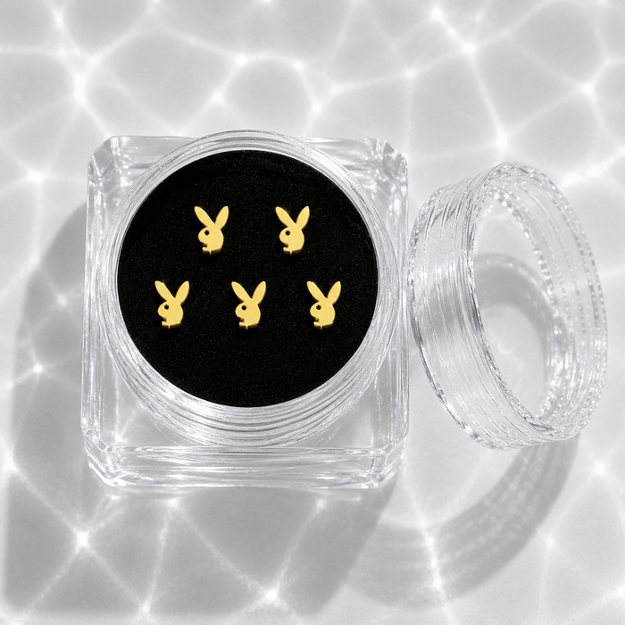 Five gold bunny tooth gem charms in a transparent acrylic display case