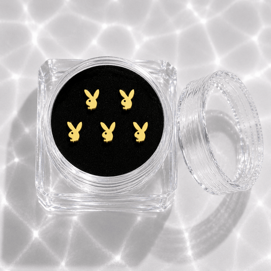 Five gold bunny tooth gem charms in a transparent acrylic display case