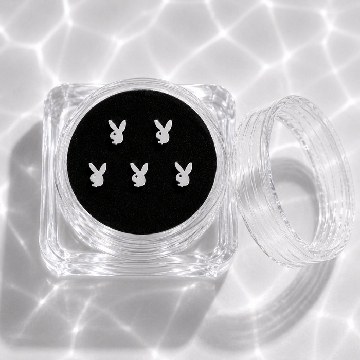 Five silver bunny tooth gem charms in a transparent acrylic display case