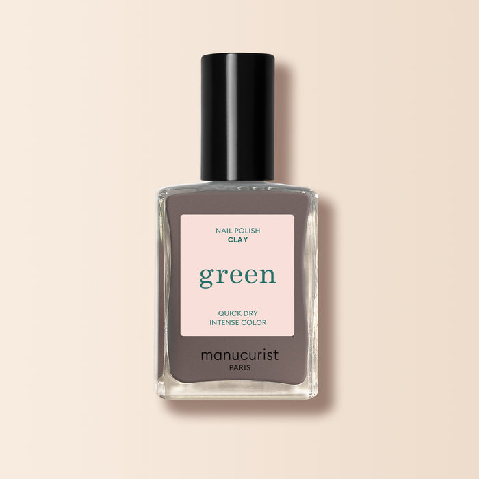 A bottle of Manucurist Clay nail polish in taupe gray, featuring a black cap and a beige label with "Nail Polish Clay, green, Quick Dry Intense Color, manucurist Paris.