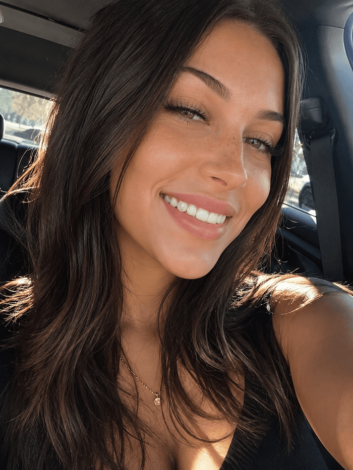 Lifestyle car selfie showing a silver cross tooth gem on a front tooth