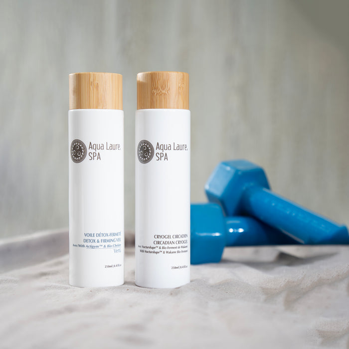 Aqua Laure SPA Detox & Firming Veil and Circadian Cryogel bottles with bamboo caps, displayed beside blue dumbbells on linen