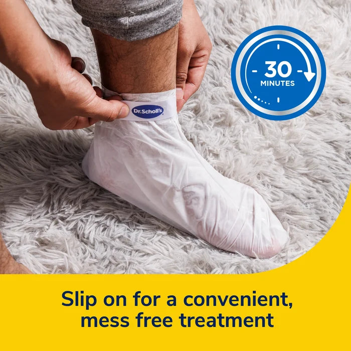 Hands slipping a foot into a white Dr.Scholl's foot mask bootie for treatment.