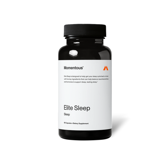 Black bottle of Momentous Elite Sleep dietary supplement on a black background. Label reads: “Momentous,” “Elite Sleep is designed to help get your sleep cycle back on track with five key ingredients that can help balance neurotransmitters and hormones to support deep, lasting sleep†.” Product name reads: “Elite Sleep,” “Sleep,” and “60 Capsules—Dietary Supplement.”
