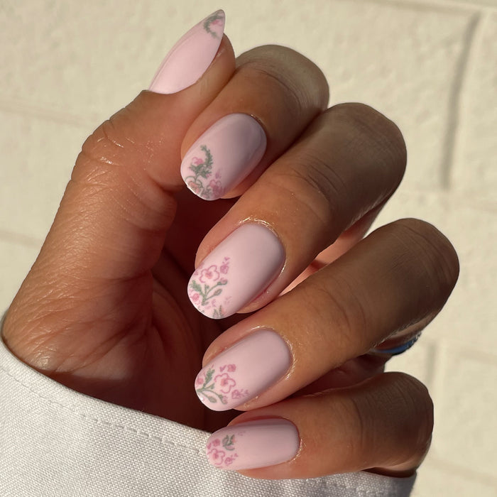 Hand showing Faded Florals - Press-On | Short | Round with soft pink base and delicate faded floral accents at nail tips