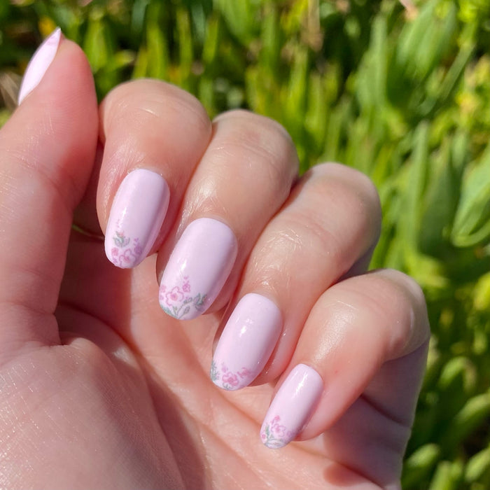 Hand with Faded Florals - Press-On | Short | Round featuring pale pink nails and intricate faded floral tips in natural light