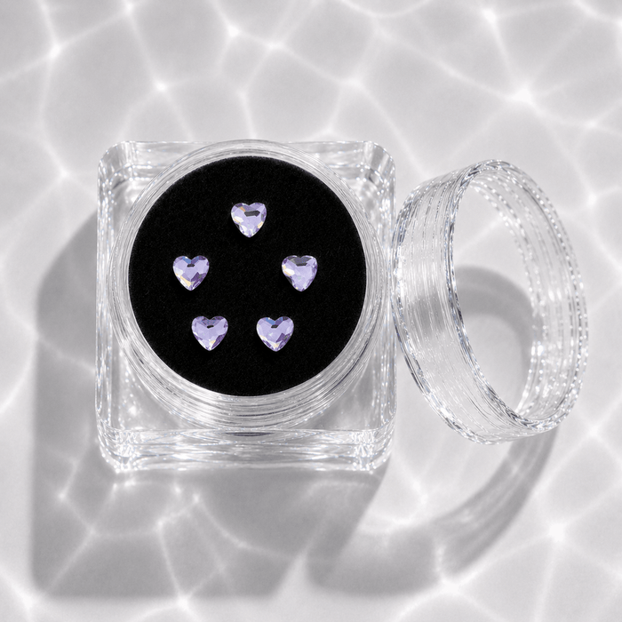 Five lavender purple crystal heart tooth gems in a clear acrylic display case