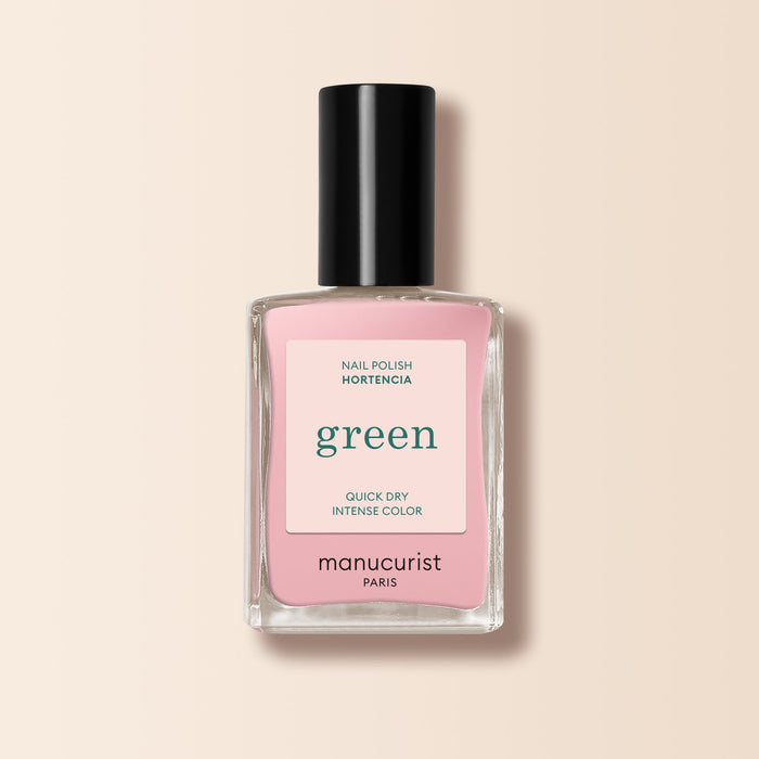 A Manucurist nail polish bottle in the shade Hortencia sits against a pale beige background. The label reads: green, quick dry, intense color. The cap is black.