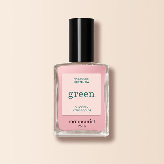 A Manucurist nail polish bottle in the shade Hortencia sits against a pale beige background. The label reads: green, quick dry, intense color. The cap is black.