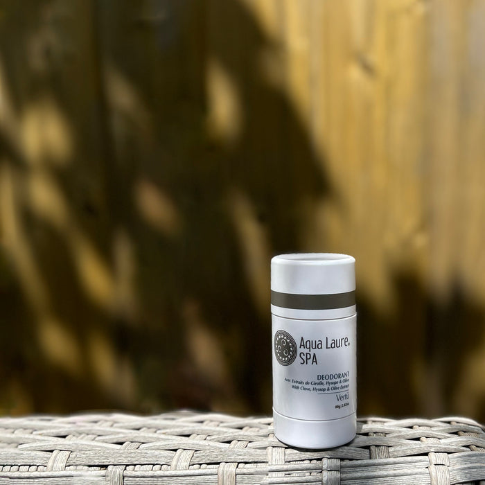 Aqua Laure SPA natural deodorant stick with clove, hyssop & olive extract, displayed on woven surface against wooden backdrop