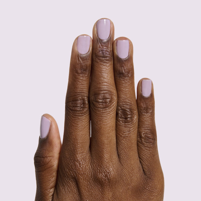 Hand with short nails painted milky sheer lavender in Lavender Stems gel polish manicure by Olive and June