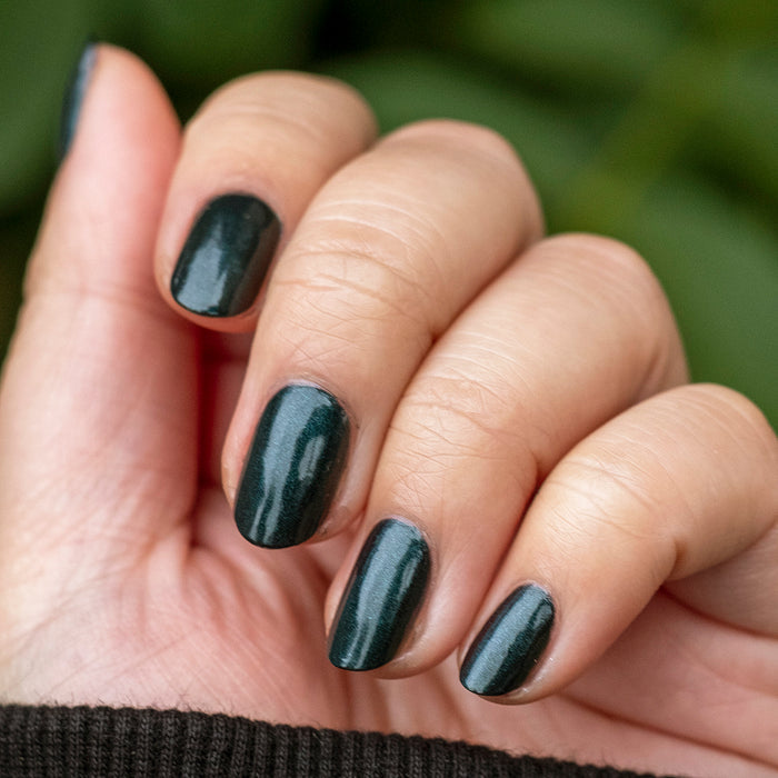 Fingernails painted in deep sparkling emerald green LL gel polish for a chic and durable manicure by Olive and June