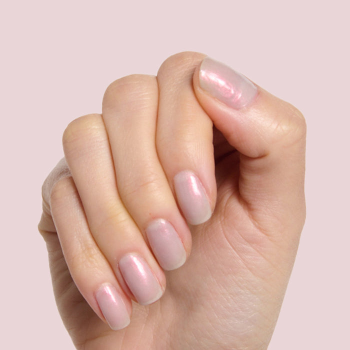 Hand with rounded nails painted in iridescent milky grey Lavender-pink Lucky Oyster polish for a soft manicure