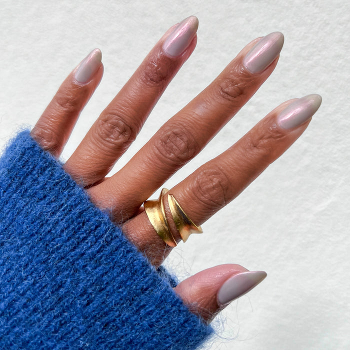 Hand with almond-shaped nails coated in iridescent Lucky Oyster gel polish showing a soft, shimmery manicure