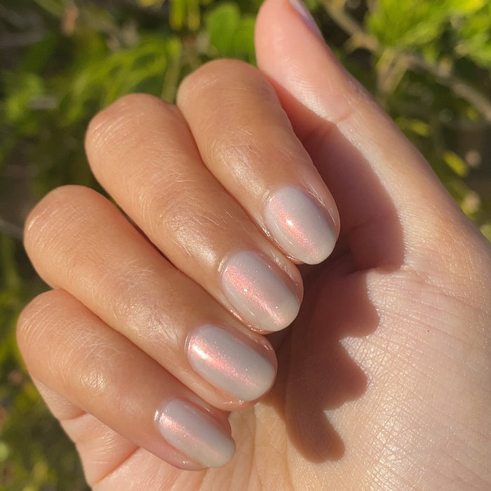 Hand with natural shaped nails painted in soft iridescent Lucky Oyster gel polish for a long-lasting manicure