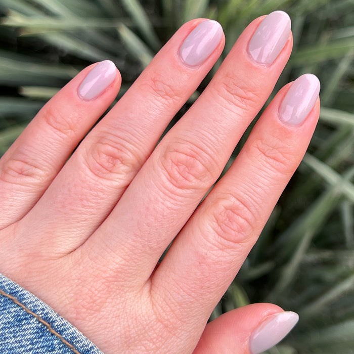 Hand with rounded nails painted in soft iridescent Lucky Oyster gel polish for a gentle long-lasting manicure