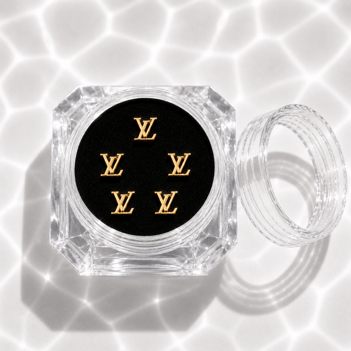 Five gold monogram tooth gem charms in a clear acrylic display case