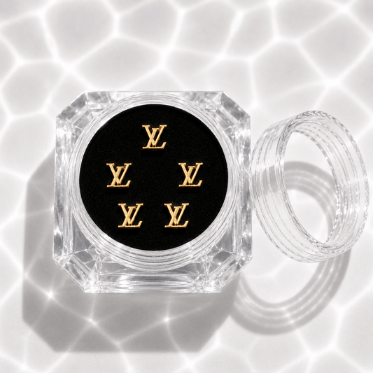 Five gold monogram tooth gem charms in a clear acrylic display case