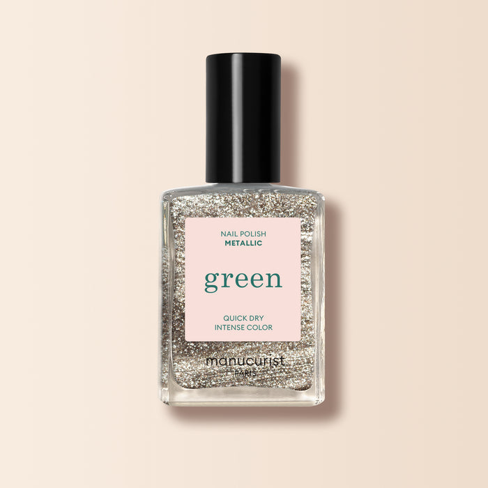 A bottle of Manucurist Metallic nail polish with metallic highlights and intense color sits on a pale pink background.