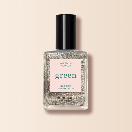 A bottle of Manucurist Metallic nail polish with metallic highlights and intense color sits on a pale pink background.