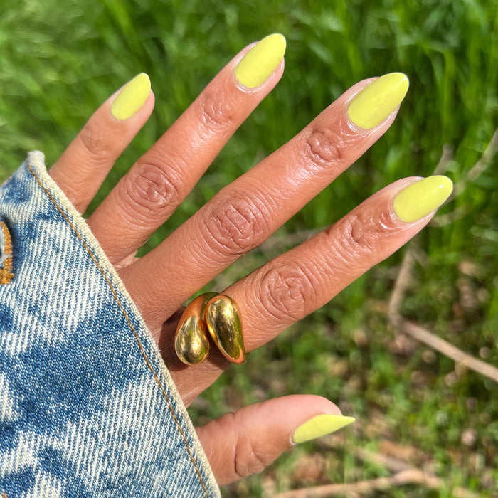 Hand with almond-shaped nails painted bright chartreuse green in Not Kale gel polish by Olive and June outdoors