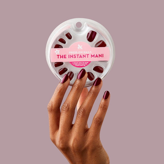 Obsessed - Press-On | Extra Short | Round dark ruby red round press-on nails on hand holding nail set packaging