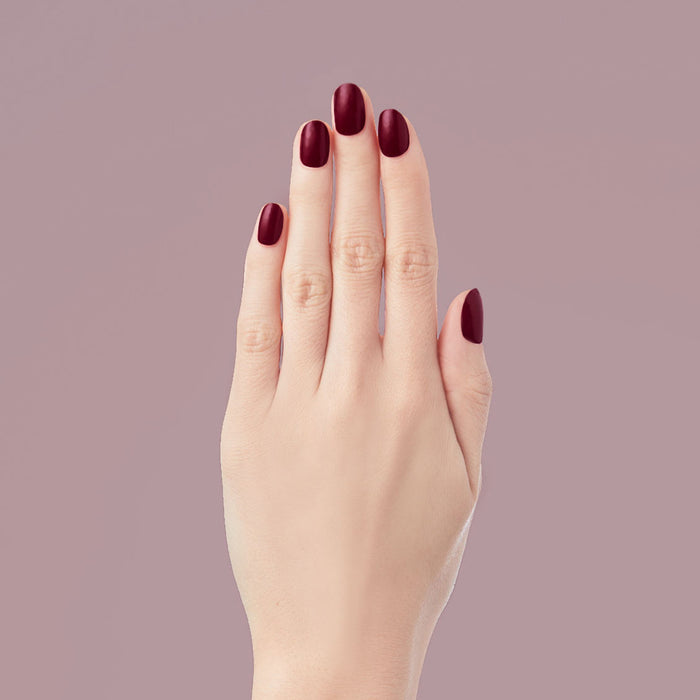 Obsessed - Press-On | Extra Short | Round hand displaying deep dark ruby red false nails for a polished mani look