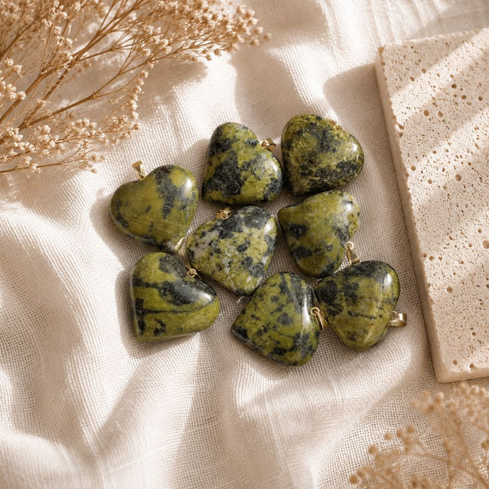 Olive Serpentine mini heart pendants displayed on a natural stone surface