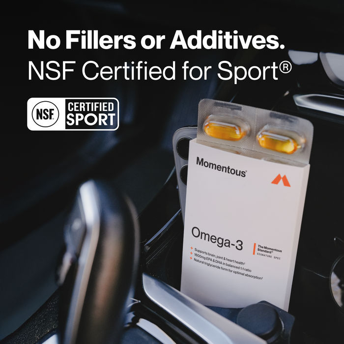 Momentous Omega-3 travel pack with two yellow gel capsules in clear blister on white packet in car cup holder.