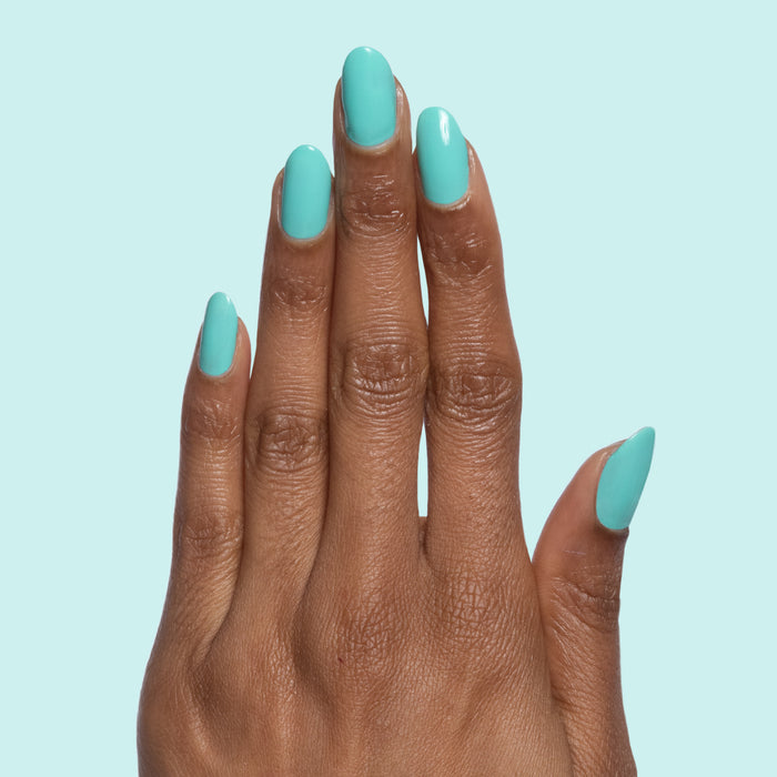 Hand with nails painted in glossy electric blue Parakeet gel polish against a light turquoise background