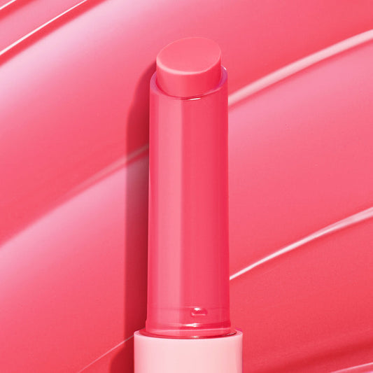 Passenger Princess, a bright pink twist-up stick of ColourPop So Juicy Plumping Gloss Balm with Peptides, shown fully extended with a dewy sheen against a matching glossy swatch background highlighting its shiny, cushiony finish.