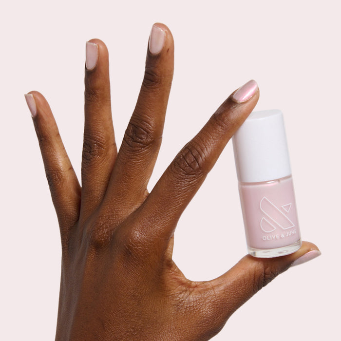 Pink Capiz nail polish shown on natural nails and held in hand for a soft pink manicure look