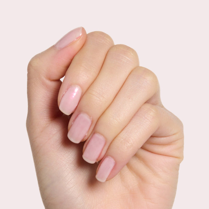 Hand with nails painted in soft shimmery pink polish showcasing Pink Capiz for a delicate manicure look