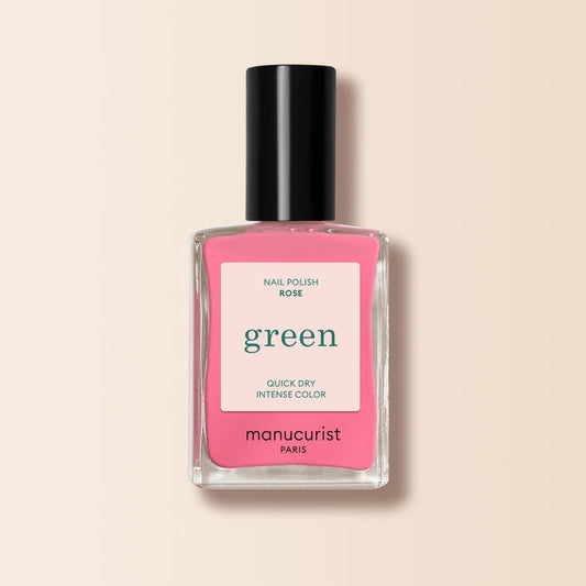 A bottle of Manucurist Rose nail polish features a rectangular clear glass bottle, black cap, and pink label, shown on a light beige background.