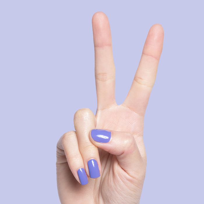 Hand with Royal quick dry polish in shiny regal purple on natural nails against soft lavender background