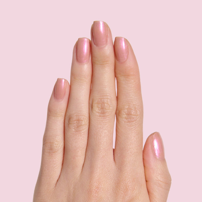 Hand with natural nails painted in glossy Sandy Scallop gel polish showing a soft milky golden iridescent manicure