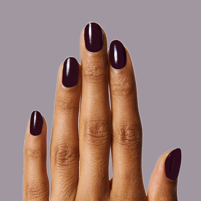Fingernails painted with deep plum SD nail polish showcasing a smooth, long-lasting mani on medium skin tone
