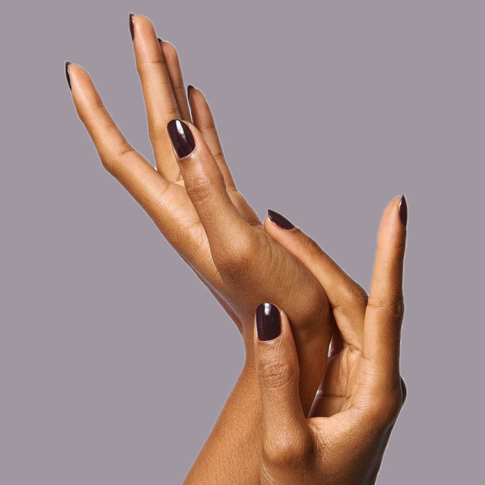 Elegant hands with nails painted in rich plum shade SD showing a smooth, long-lasting manicure on medium skin tone