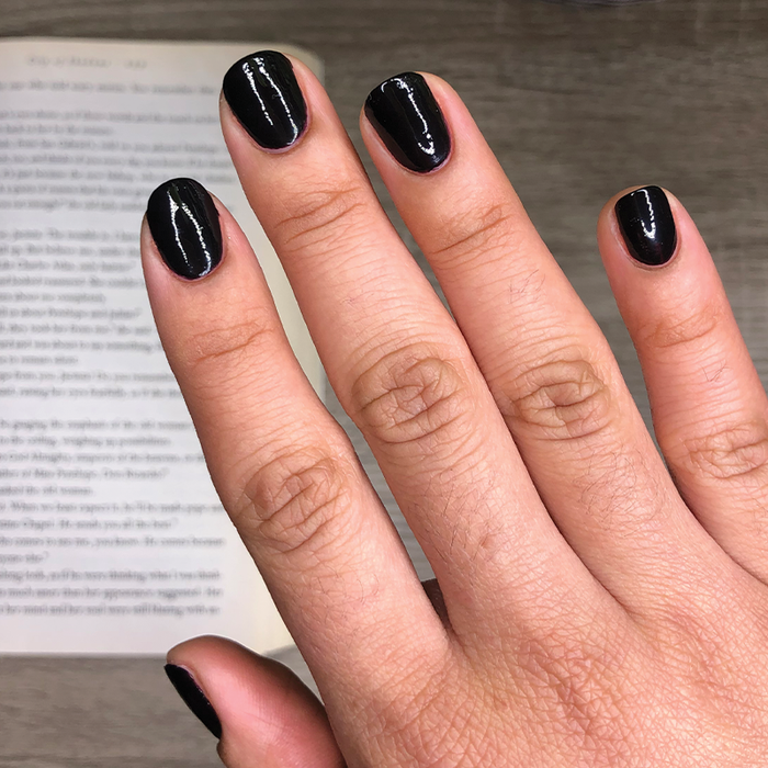 Hand with nails painted in glossy black using SD nail polish showing a sleek, long-lasting manicure on medium skin tone