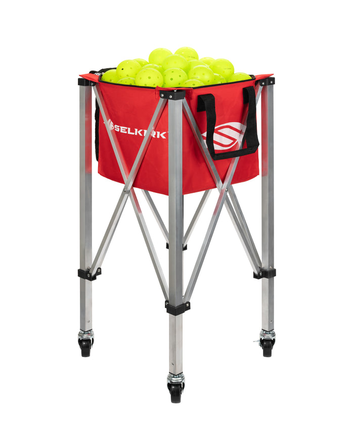 Red SELKIRK collapsible ball hopper on aluminum folding frame with caster wheels, filled with neon yellow practice balls