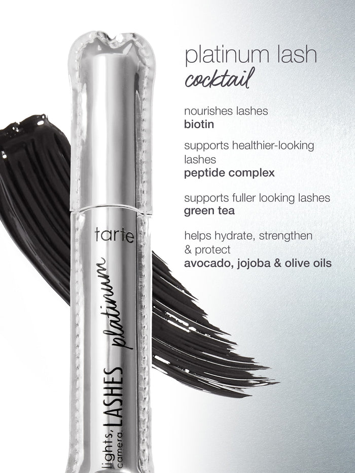 A silver mascara tube labeled tarte lights, camera, lashes platinum rests on a black mascara smear. Text lists ingredients: platinum lash cocktail, nourishes lashes biotin, supports healthier-looking lashes peptide complex, supports fuller looking lashes green tea, helps hydrate, strengthen & protect avocado, jojoba & olive oils.