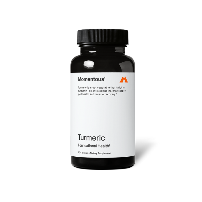A black bottle of Momentous Turmeric dietary supplement is centered on a black background with a white label. Text on the label reads: “Momentous®” “Turmeric is a root vegetable that is rich in curcumin—an antioxidant that may support joint health and muscle recovery.†” “Turmeric” “Foundational Health†” “60 Capsules—Dietary Supplement”