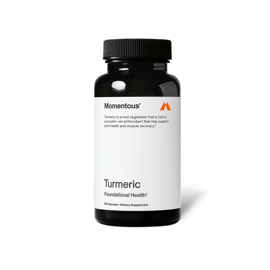 A black bottle of Momentous Turmeric dietary supplement is centered on a black background with a white label. Text on the label reads: “Momentous®” “Turmeric is a root vegetable that is rich in curcumin—an antioxidant that may support joint health and muscle recovery.†” “Turmeric” “Foundational Health†” “60 Capsules—Dietary Supplement”